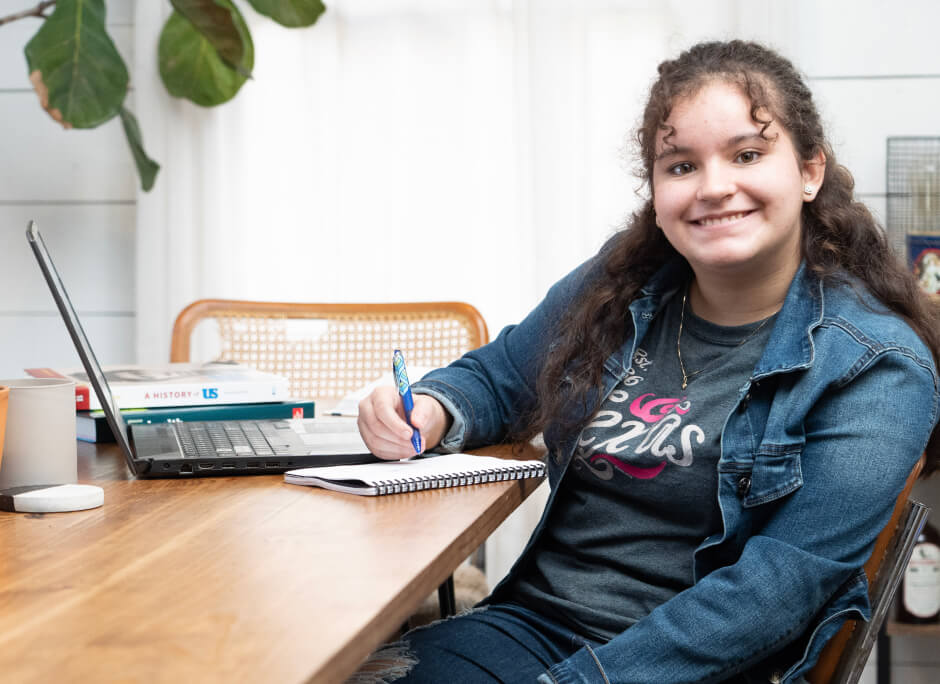 Elèv yo souri nan kamarad la, chita sou tab li ak imaj laptop li